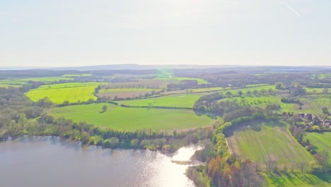 Sweeping drone pullback over Elsecar green terrain with rolling fields and farmland, England UK