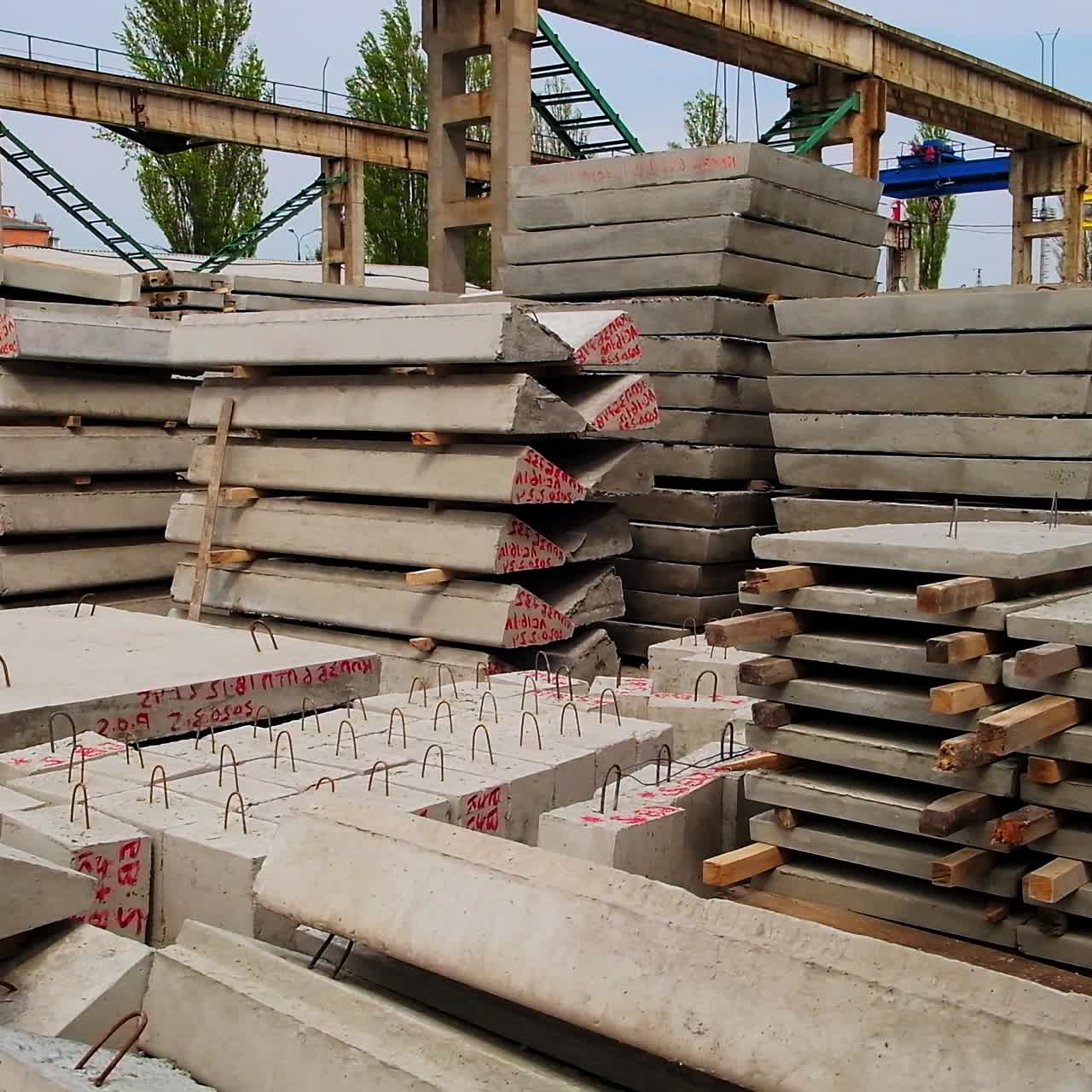 Ferroconcrete pallets and blocks piled together at the construction site. High metal construction supports at the backdrop