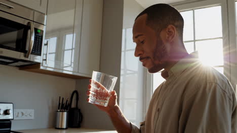 man drinking water in kitchen