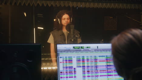 vocalist comes in soundproof room and sings vocalist comes in soundproof room and sings lyrical composition into microphone experienced sound engineer works in audio recording studio computer screen showing the daw software music production