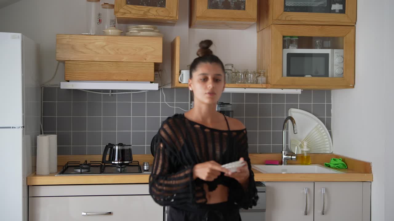 Donna in cucina che tiene in mano dei bicchieri