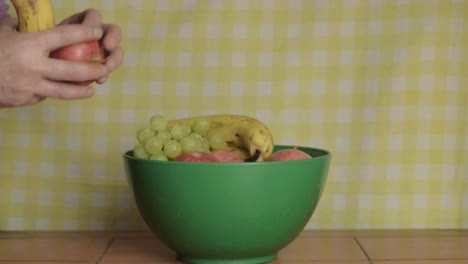 hand picking fruit from from a choice of fruit in a bowl wide shot