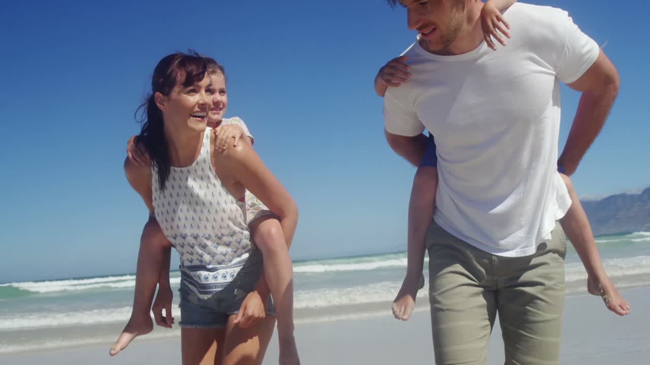 부모 들 이 해변 에 있는 자녀 들 에게 짐 을  ⁇ 고 다니는 것