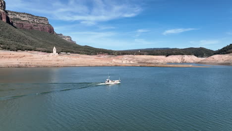 Aerial-fisherman-motor-boat-in-Sau-reservoir-with-resurfaced-church-behind