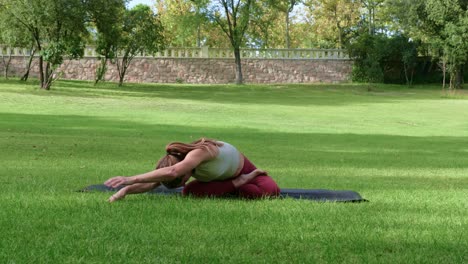 flexible woman doing forward bend in park