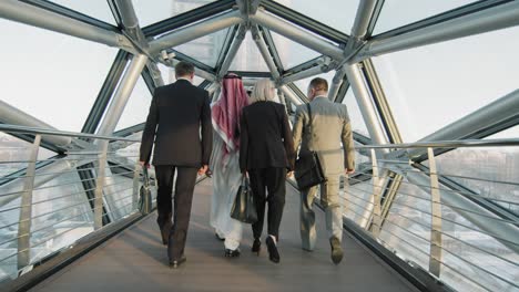 diverse team of business partners walking along glass bridge