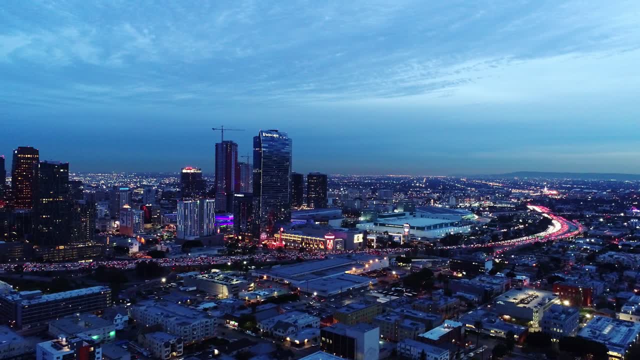 Backward drone flight capturing the vibrant cityscape of Los Angeles at twilight