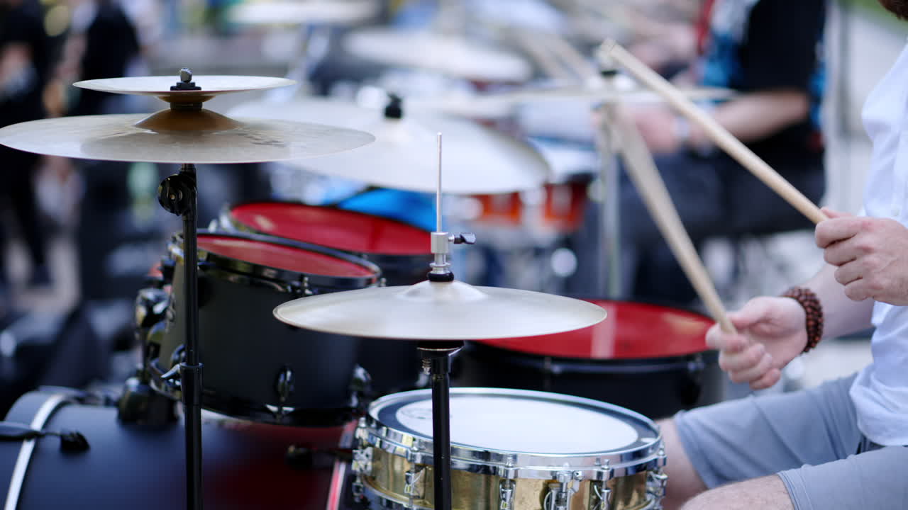 Close up of man playing red drums outside