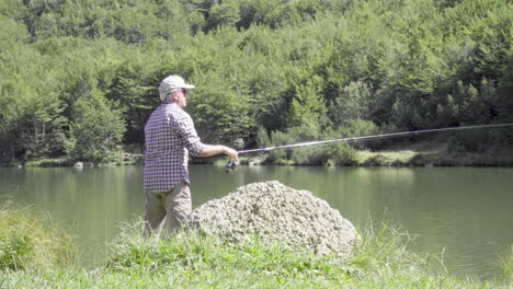 man fishing ion a mountain lake, medium shot 4k