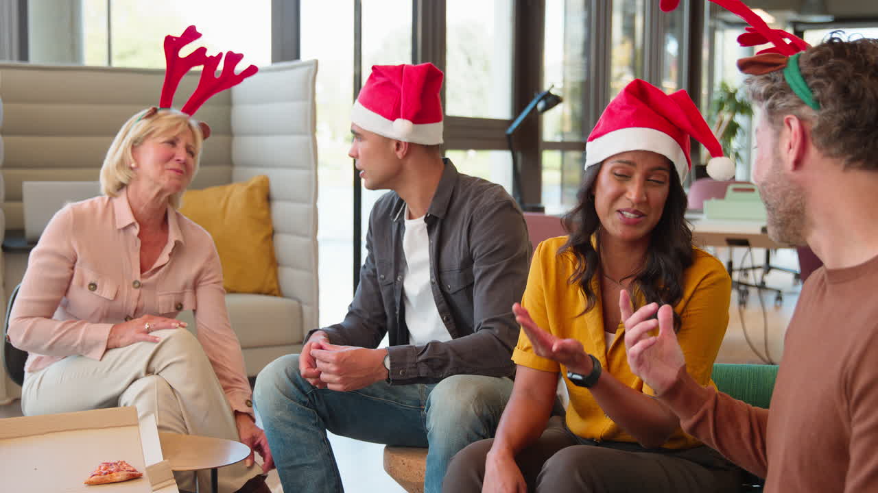 Funcionários comemorando uma festa de Natal no escritório, fantasiados com chifres de rena e gorro de Papai Noel