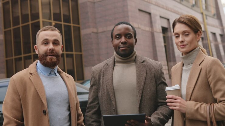 Bottom view of caucasian businesswoman holding coffee, african american man watching to a tablet and caucasian man in the street in autumn