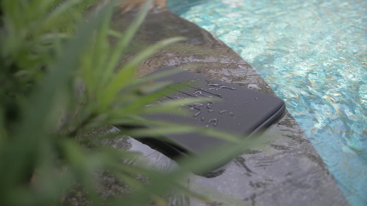 선이 새겨진 검은색의 기본 방수 노트북 케이스는 물방울과 물방울이 있는 수영장 옆에 있습니다.