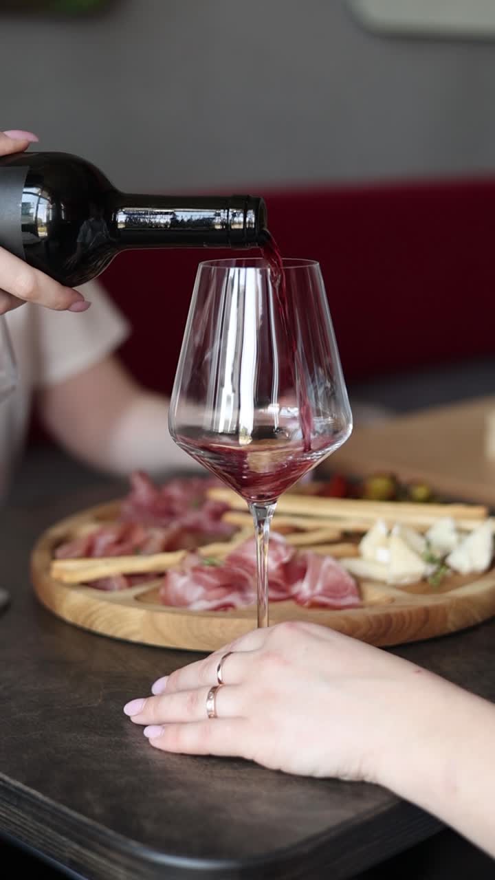 Sirviendo vino tinto con tabla de charcutería