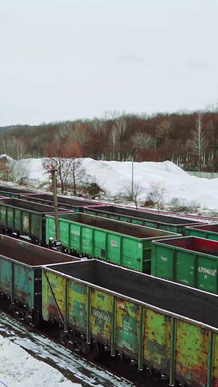 Long rows with old cargo containers for the transport of imports and exports stand on the edge of the forest in the winter on the border zone. Aerial view. Vertical video