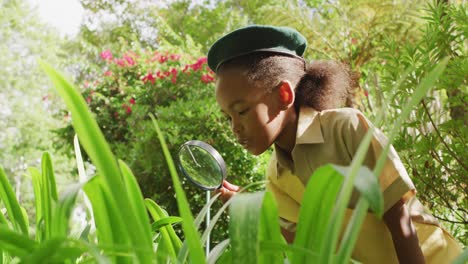 animación de una niña afroamericana en disfraz de explorador usando lupa en el jardín