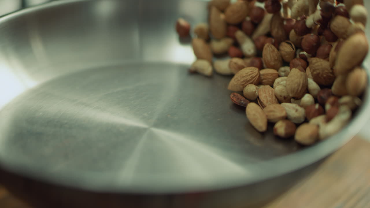 Mix of nuts frying on metal pan. Closeup nuts tossing in slow motion.