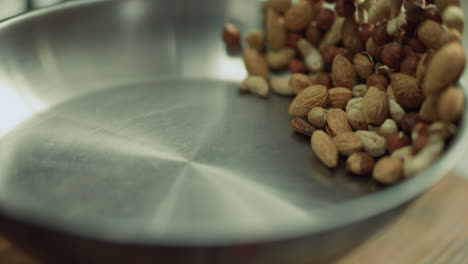 mix of nuts frying on metal pan. closeup nuts tossing in slow motion.