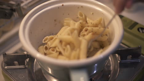 Cocinar-Espagueti-Aglio-E-Olio-Penne-Pasta-En-Tazón-Blanco-Sobre-Cuchara-De-Estufa,-Primer-Plano