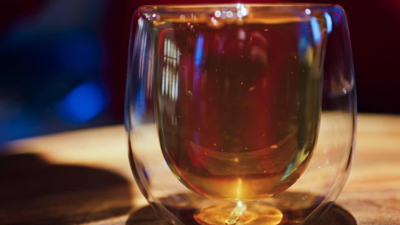 Close up of a woman pouring tea from a French press into a double glass cup at a restaurant