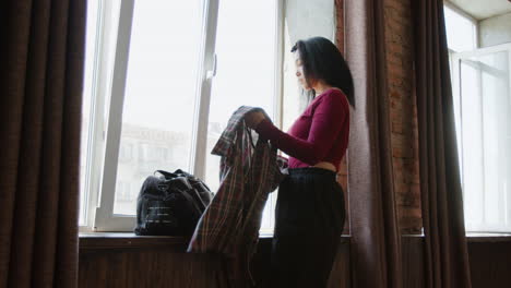 woman by the window getting ready, with a duffel bag