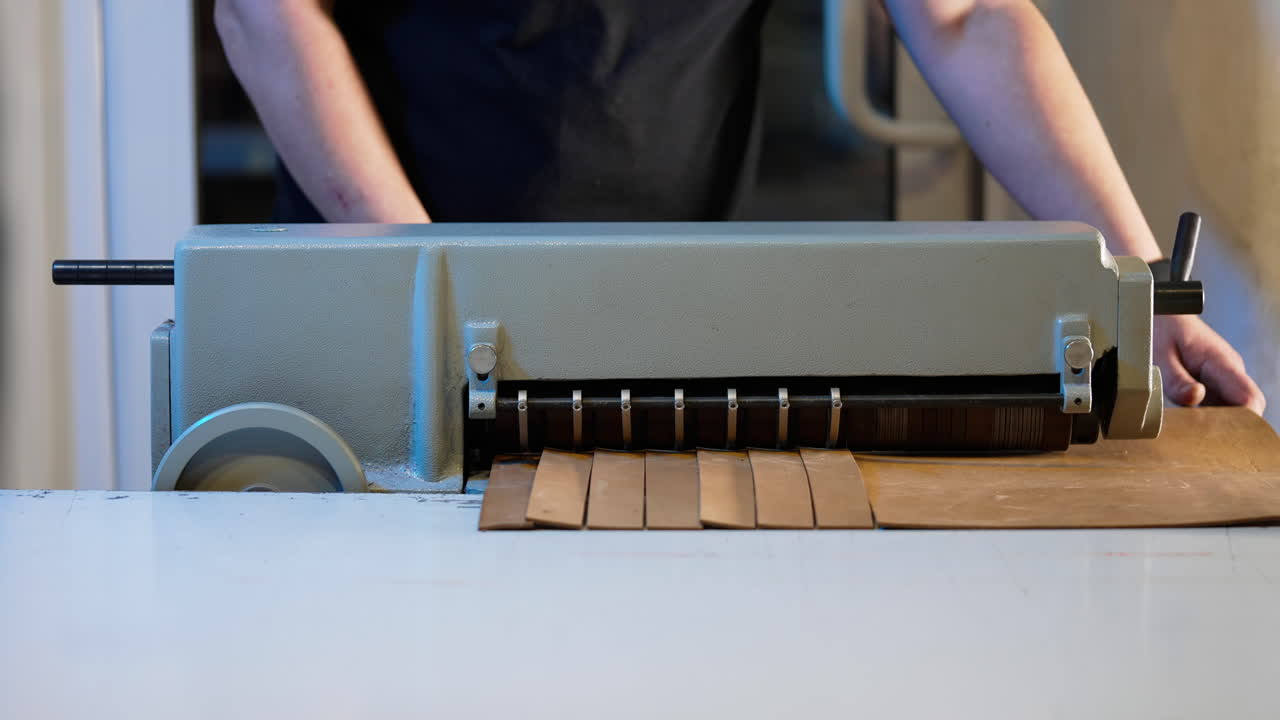 Master cutting leather on a special machine in workshop. Professional craftsman working in sewing industry. Procedure for the manufacture things from leather.