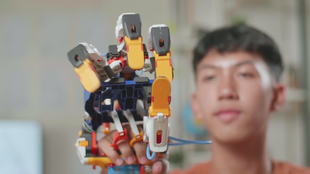 만족 한 아시아 소년 이 집 에서 노트북 을 사용 하는 동안 사이보그 손 을 보고 확인 하는 근접 사진