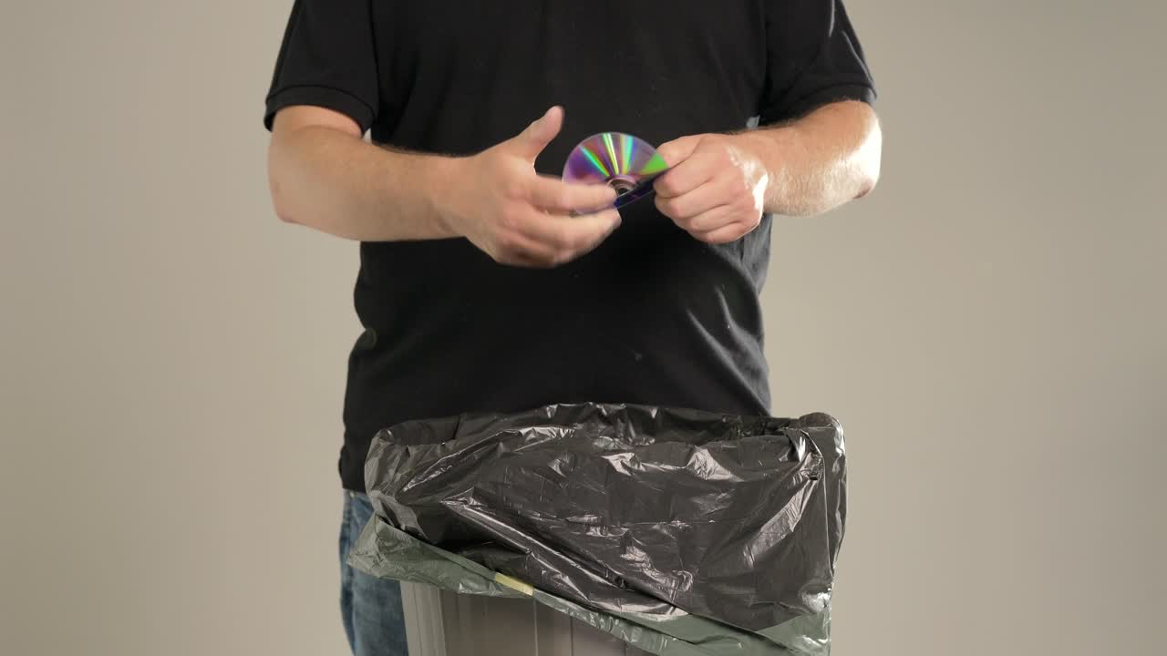 un hombre está tirando cd y dvd rotos a la basura