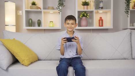 niño adicto al teléfono juega juegos en el teléfono en casa