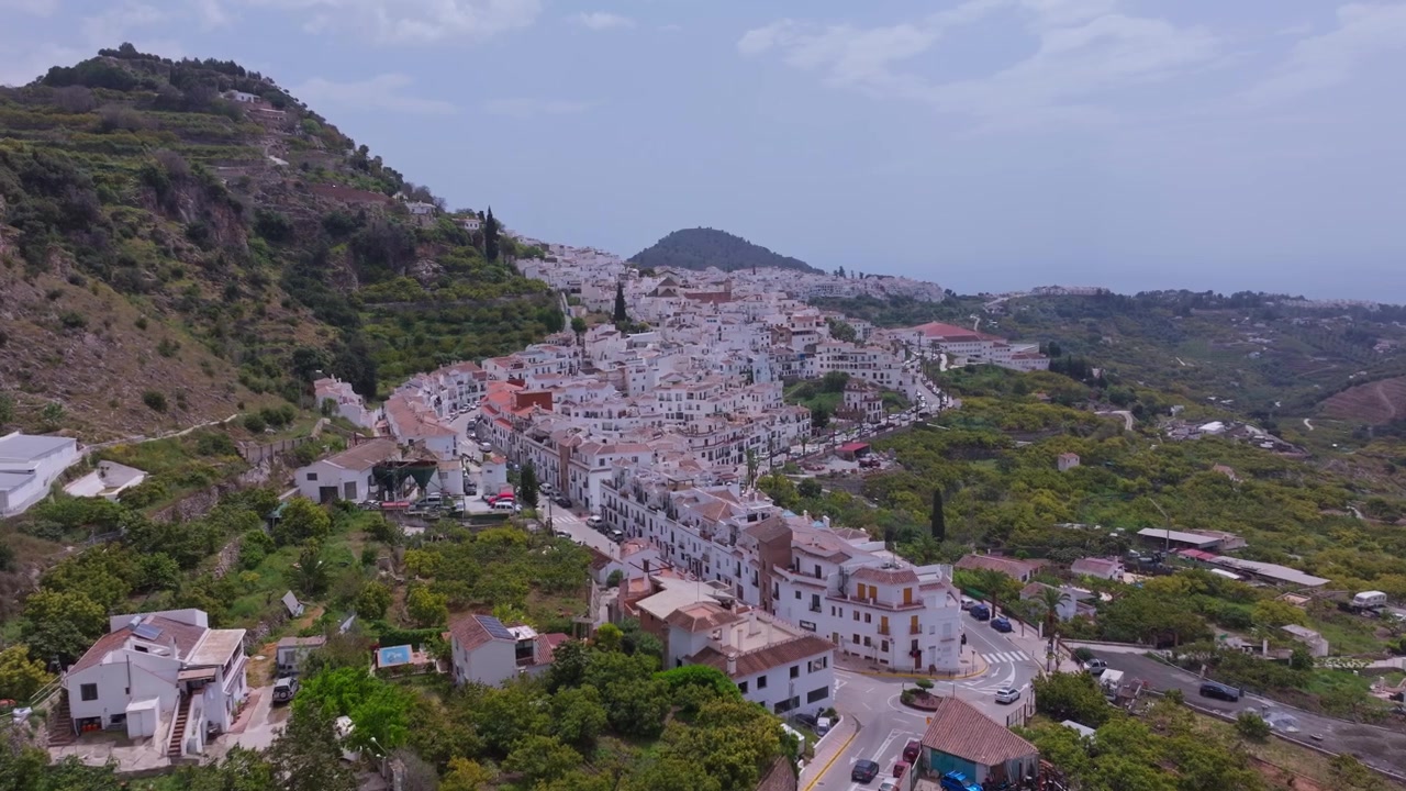 Riprese con drone di Frigiliana in Andalusia, Spagna, che mostrano un tranquillo villaggio imbiancato a calce, strade collinari tortuose e auto che guidano sotto montagne nebbiose