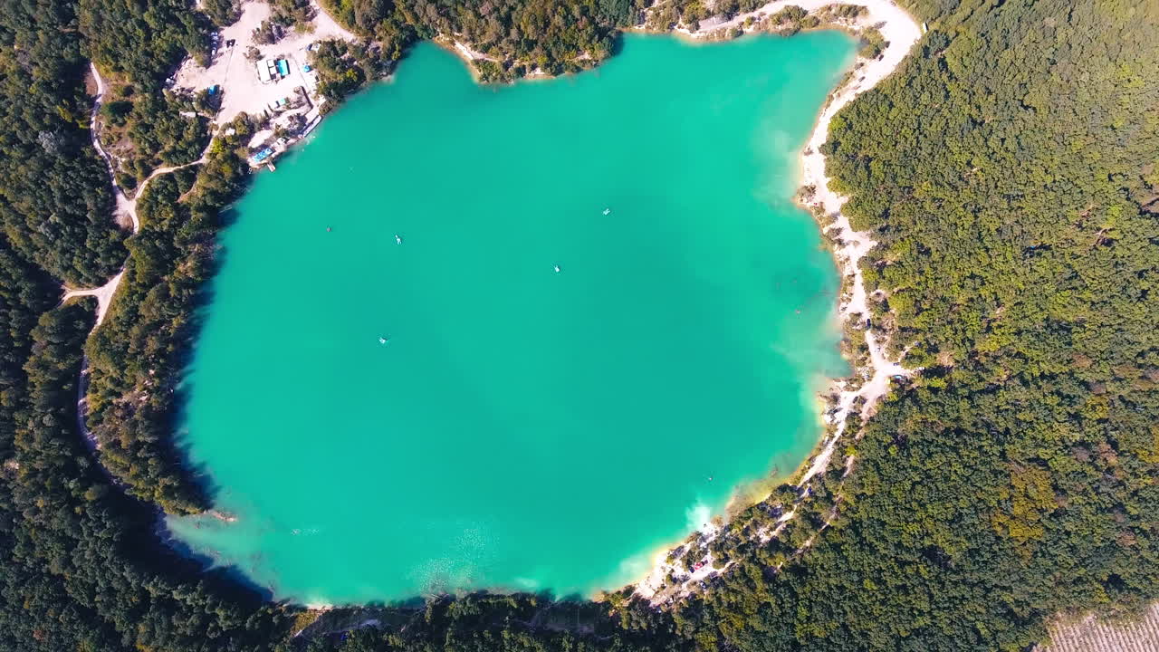 Breathtaking scenery over the turquoise lake in the middle of the thick woods. Deep waters surrounded by the beautiful scenery. Birds eye view.