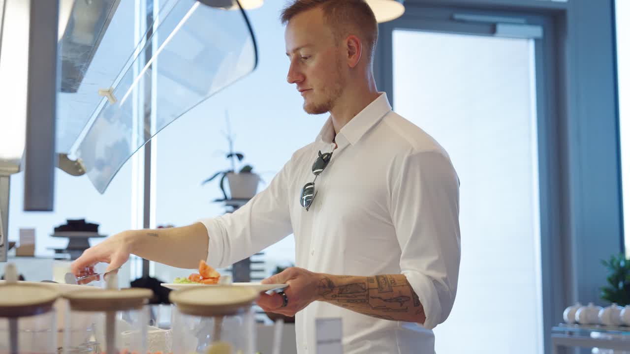Uomo attraente che sceglie la colazione nel ristorante di un hotel, vista laterale