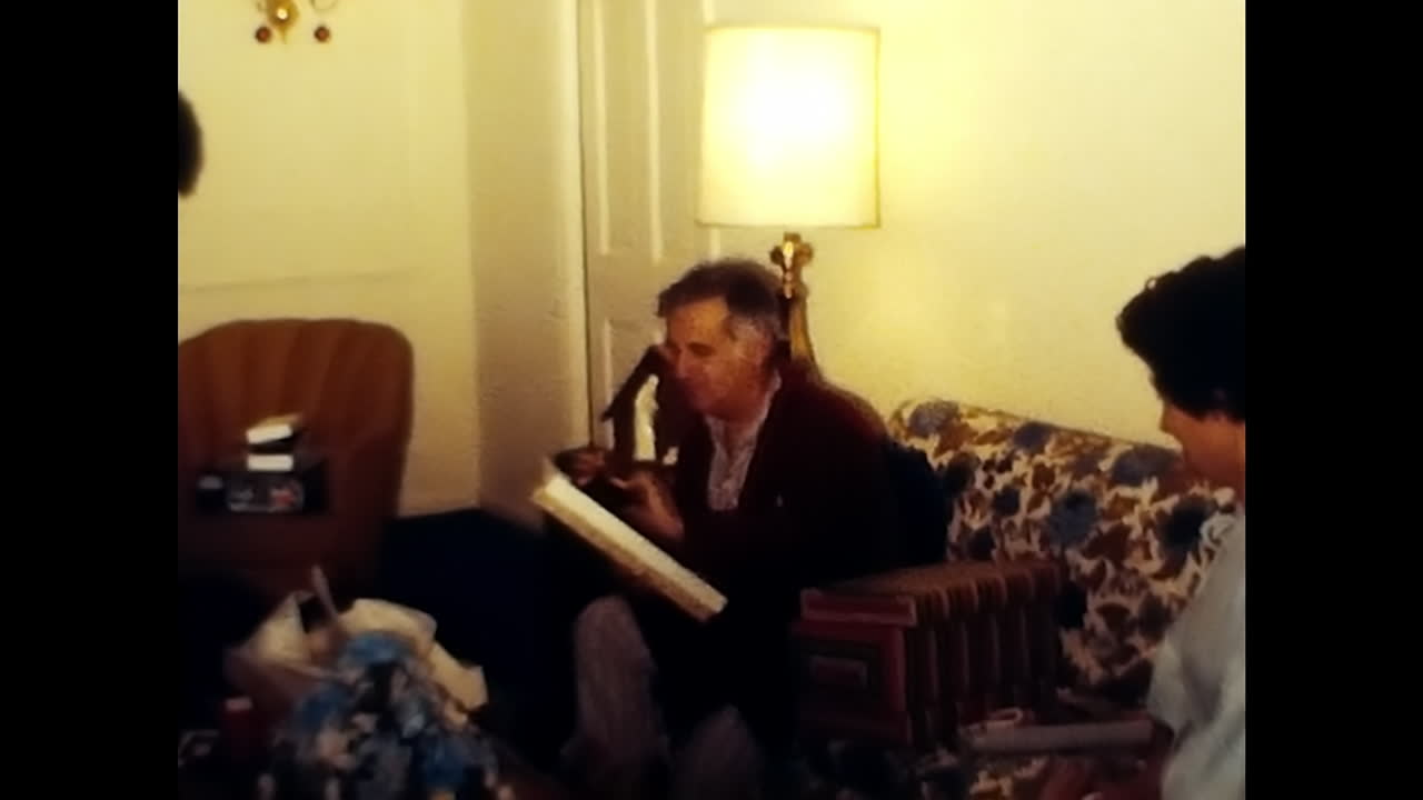 Group of People Sitting in 1970s USA Living Room. CIRCA USA - 1970s: A vintage video capturing a group of people comfortably seated and engaged in conversation inside a living room from the 1970s in the United States of America.