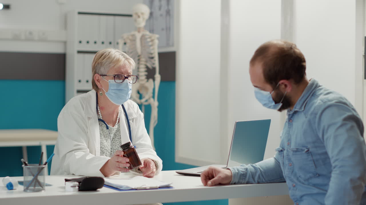 Female physician giving bottle of pills to sick man at checkup visit