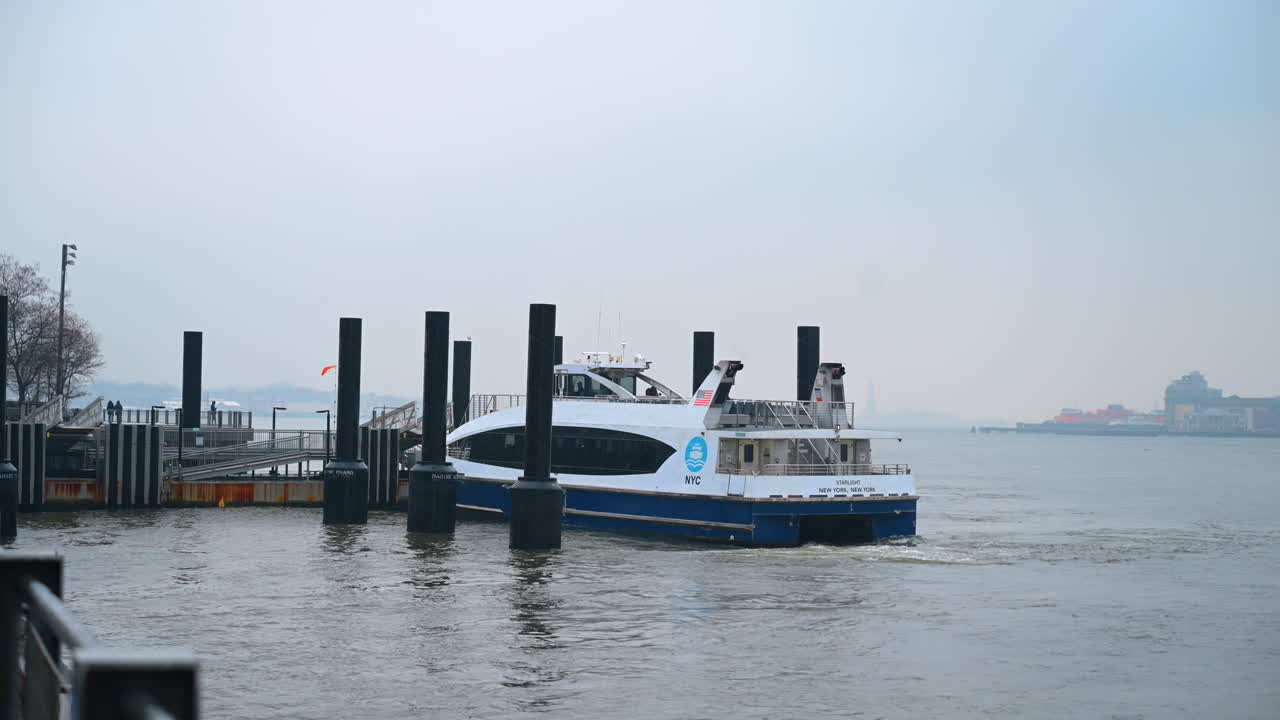 New York, USA, 24 dicembre 2025: traghetto di NYC al molo invernale. Traghetto di NYC che attracca al molo invernale con fiume calmo e cielo nuvoloso