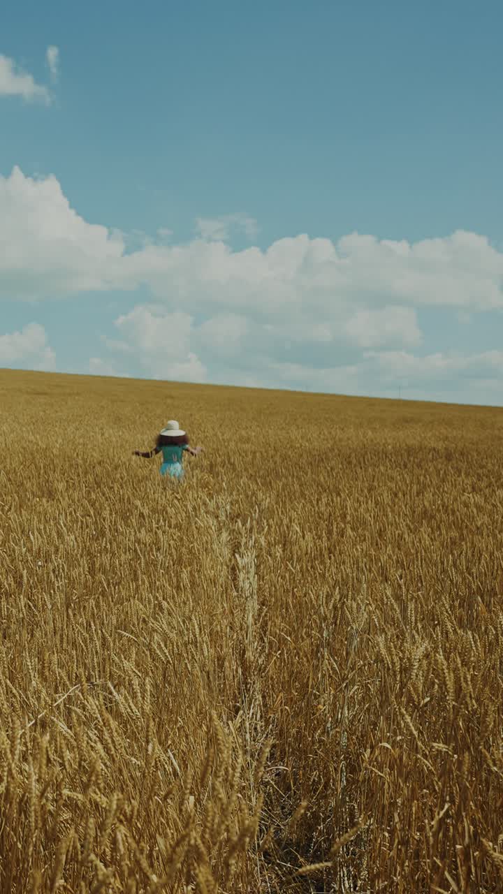Woman walking through a wheat field on a sunny day