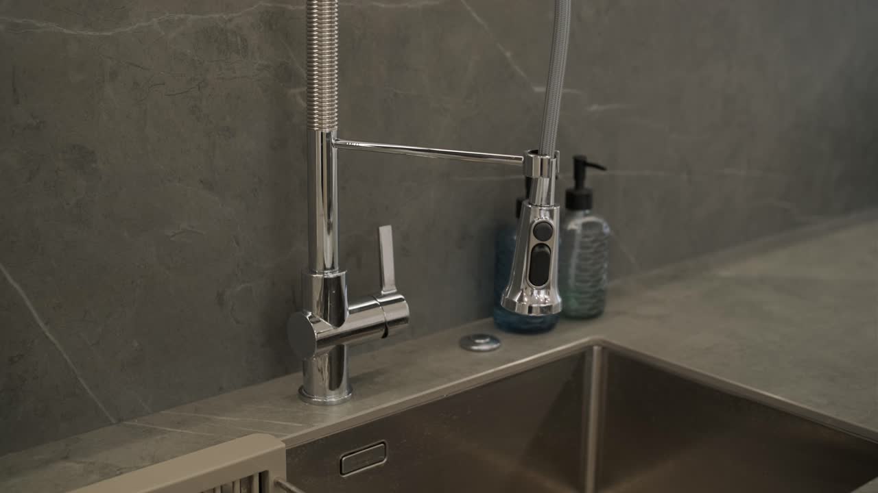 vista en primer plano de un fregadero de cocina contemporáneo con un grifo de diseño de alta gama contra un backsplash de piedra gris