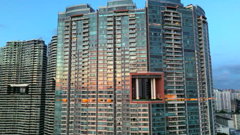 Shiny-residential-high-rise-building-with-sunset-reflection-in-glass-exterior---drone-orbit-shot