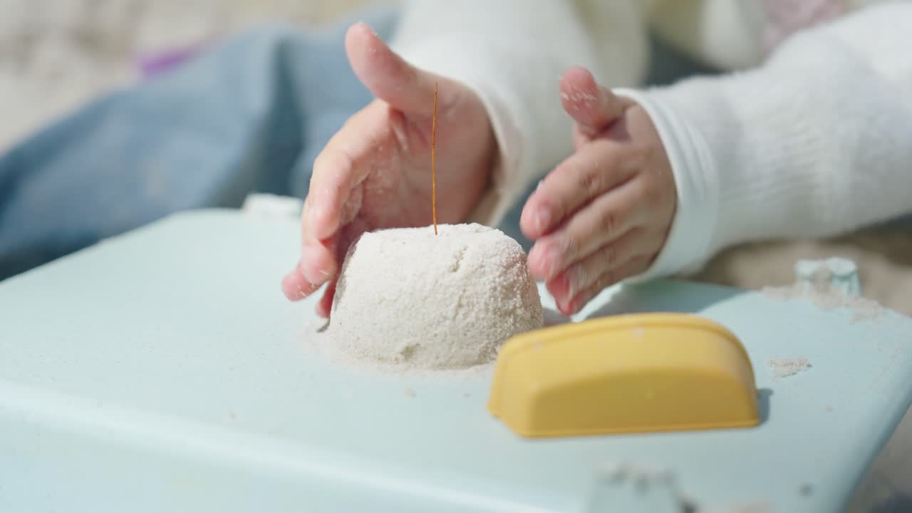 黄色いおもちゃのある遊び場で円筒形を作る幼児の手。