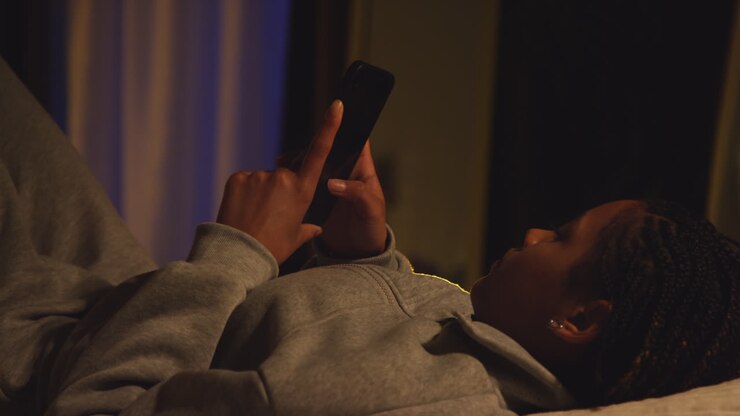 Ragazza adolescente che usa uno smartphone a letto di notte