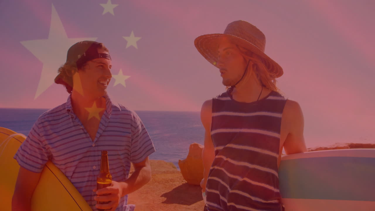 Holding surfboards by ocean, two men talking with Chinese flag animation