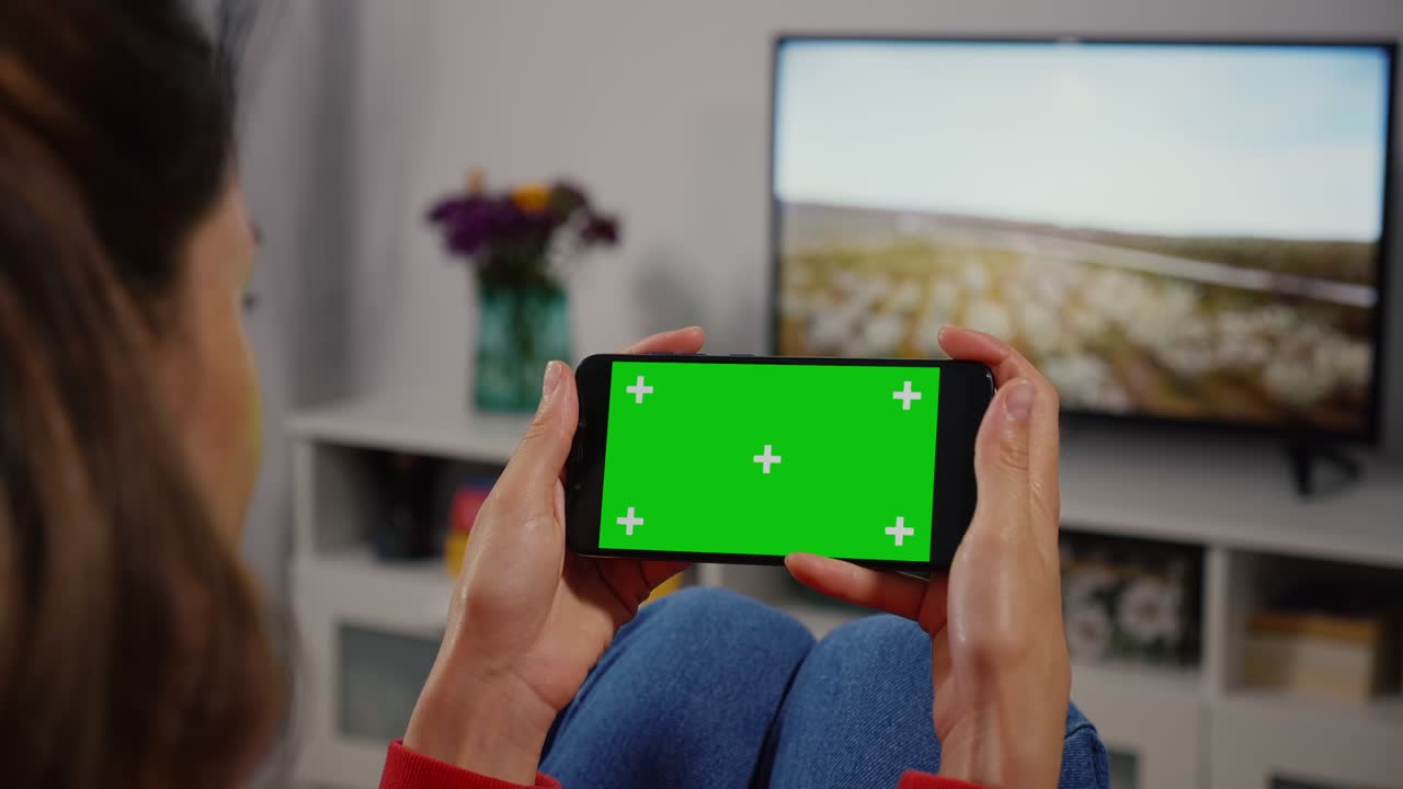 초록색 화면의 스마트폰을 사용하는 여성