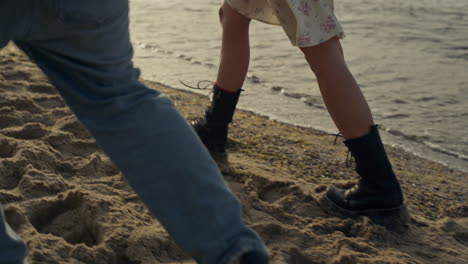 Stylish-woman-and-man-feet-walking-on-beach.-Couple-holding-hands-at-sunset