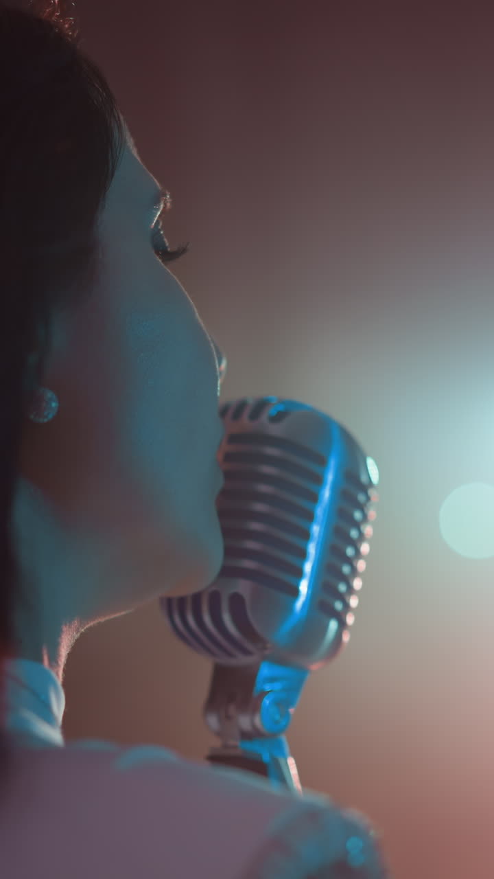 Close-up side view of a singer in a white gown with beaded fringe, performing with a vintage microphone. Soft, glowing lights create an intimate atmosphere