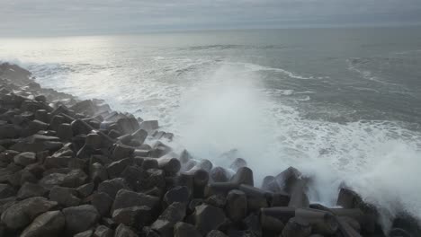 Las-Olas-Chocan-Contra-Las-Rocas,-El-Agua-De-Mar-Espumosa-Fluye-Por-La-Superficie-De-La-Roca,-El-Océano-Turbulento