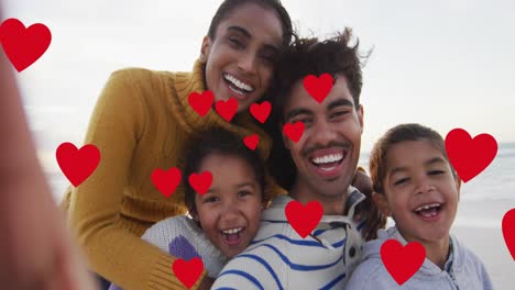 Animation-of-red-hearts-over-biracial-couple-with-son-and-daughter-on-beach