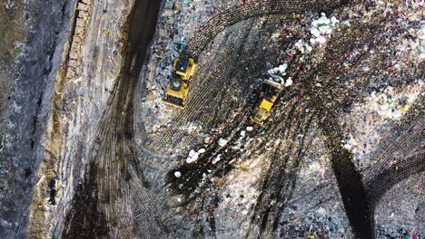 Aerial-flyover-landfill-full-of-trash,-pollution-environmental-problem,-garbage,-trucks-dump-waste-products-polluting-in-a-dump,-wide-angle-birdseye-drone-shot-rotating