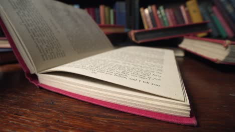 Slow-motion-macro-view-of-book-with-red-cover-is-closed-shut-on-desk-in-library