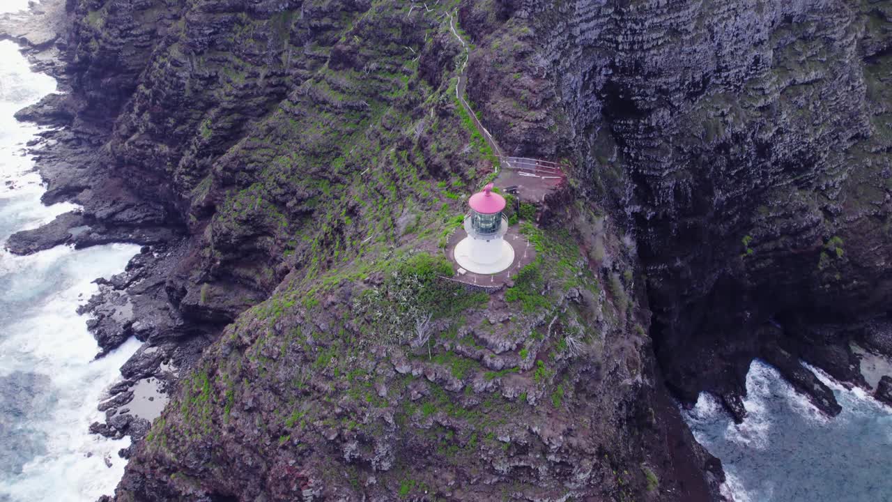 aerial view above Makapu'u Point Lighthouse on the island of Oahu in Hawaii as it sits isolated on a cliff top above the raging Pacific Ocean waters