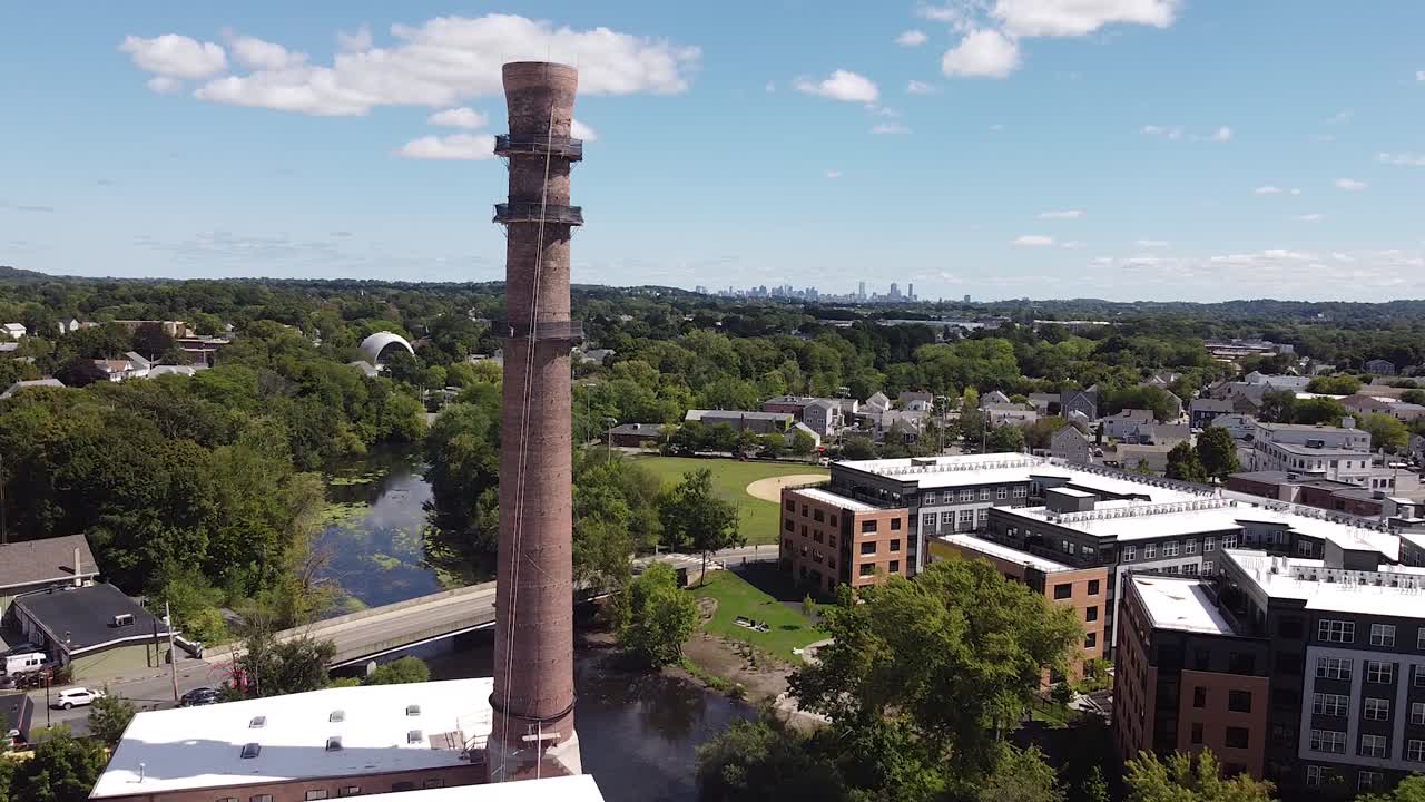 A historic smokestack outside of Boston, with the city skyline in the distance.