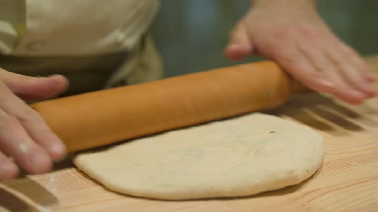 primer plano del chef en la cocina abierta del restaurante preparando la masa para el pastel tradicional de osetia